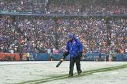 A grounds crew worker blows snow off the yard lines during the first quarter of an NFL division round football game between the Buffalo Bills and the Cincinnati Bengals, Sunday, Jan. 22, 2023, in Orchard Park, N.Y. (AP Photo/Adrian Kraus)