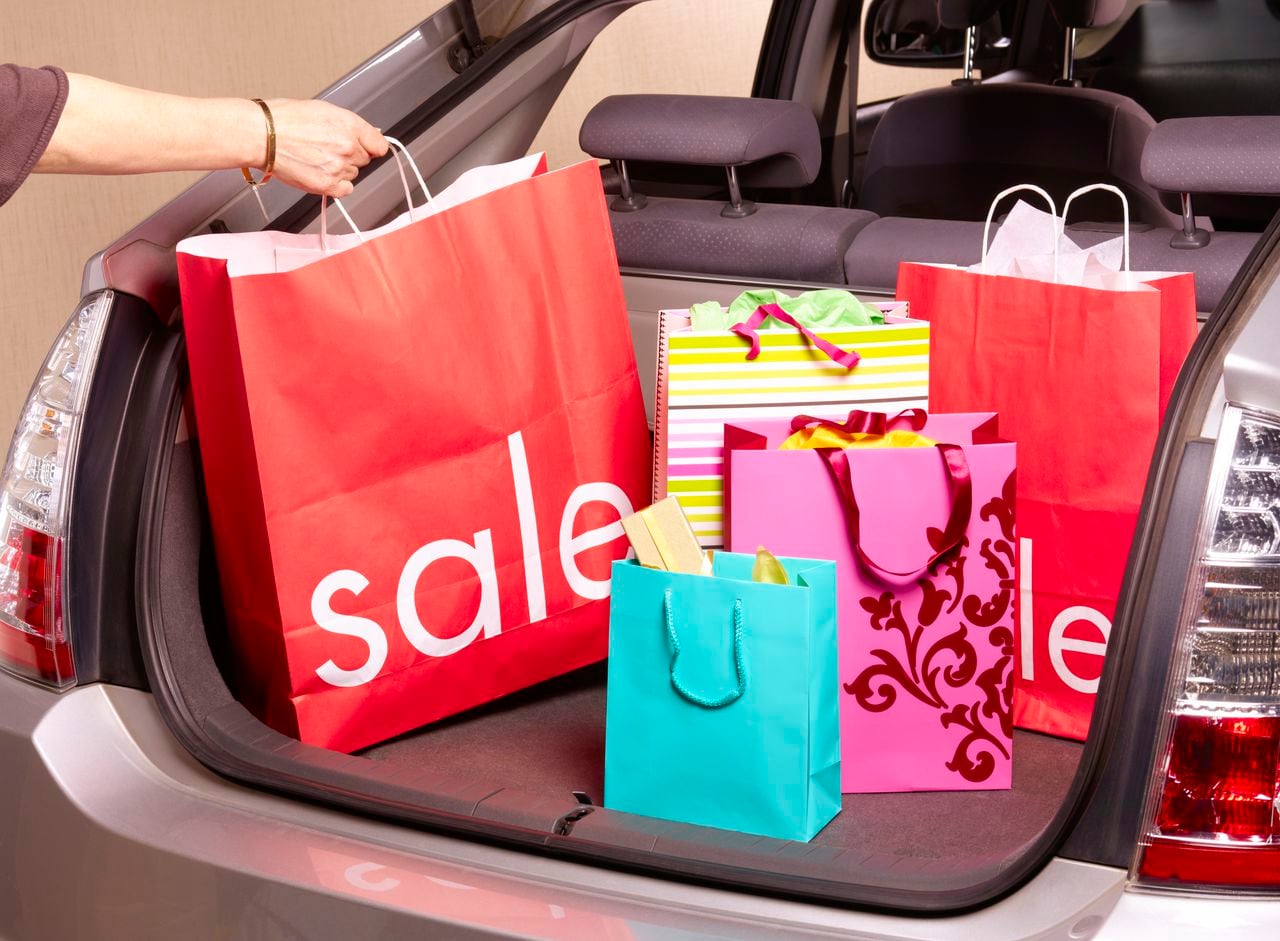 A person places shopping bags in the back of a vehicle