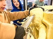 Sawyer Locke of Cazenovia helps deconstruct the 2023 New York State Fair butter sculpture. (Charlie Miller | cmiller@syracuse.com)