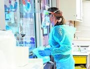 A nurse looks at a patient in the COVID-19 ICU at the Upstate University Hospital in December 2020.