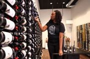 Sommelier and business owner Cha McCoy restocks bottles at The Communion Wine + Spirits, her shop in downtown Syracuse.